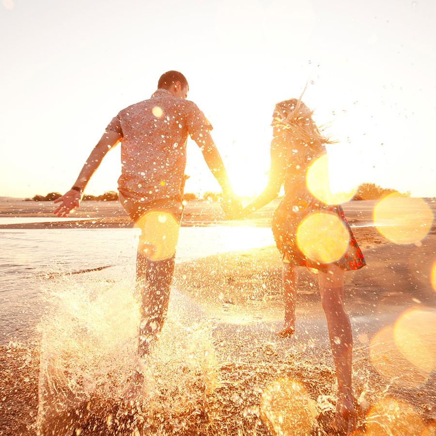 A happy couple running on the beach who are physically fit- Cerulean