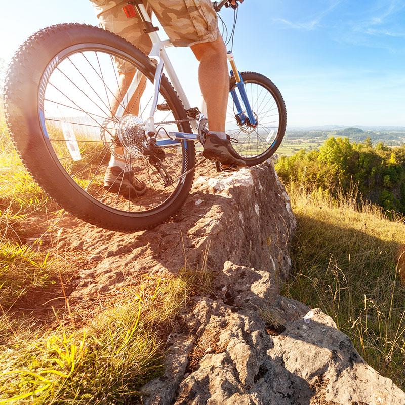 A mountain biker in action on rocks at downhill trail for healthy lifestyle exercise and extreme sports- Cerulean